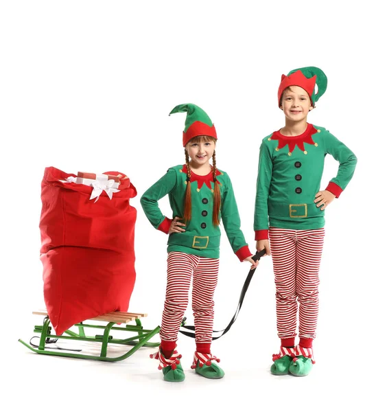 Crianças em traje de elfo e com saco de Papai Noel no trenó contra fundo branco — Fotografia de Stock
