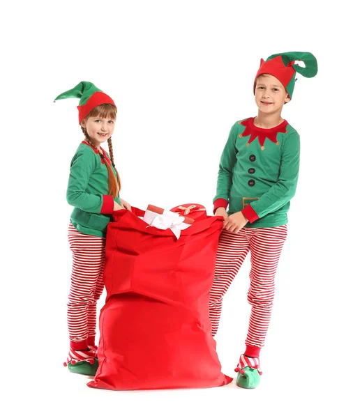 Little children in costume of elf and with Santa Claus bag full of gifts on white background — Stock Photo, Image