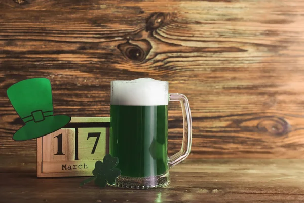 Mug of green beer for St. Patrick's Day and calendar on wooden table — Stock Photo, Image