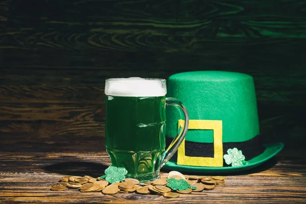 Taza de cerveza verde para el Día de San Patricio, sombrero de duende y monedas en la mesa de madera — Foto de Stock