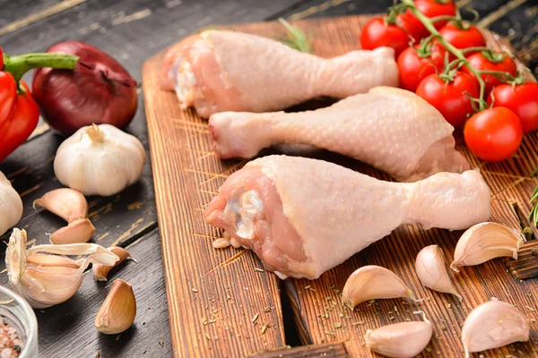 Raw chicken drumsticks on wooden board — Stock Photo, Image