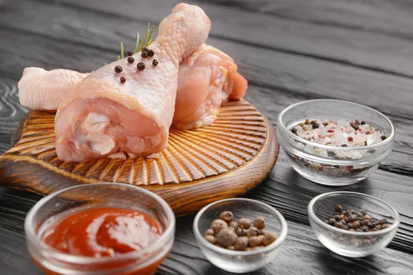 Raw chicken drumsticks and spices on wooden background — Stock Photo, Image