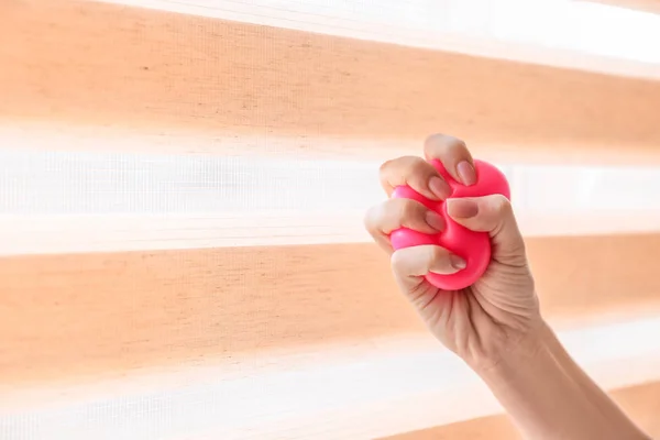 Female hand squeezing stress ball near window — Stock Photo, Image