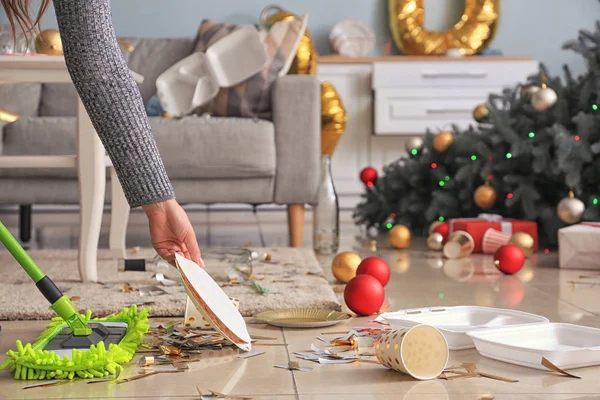 Женщина убирает комнату после новогодней вечеринки — стоковое фото