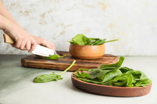 Woman cutting fresh green spinach on table — Stock Photo, Image