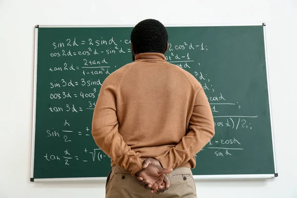 Profesor de matemáticas afroamericano cerca de pizarra en el aula — Foto de Stock