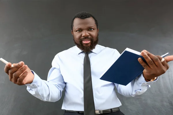 Professor afro-americano irritado perto de quadro negro em sala de aula — Fotografia de Stock