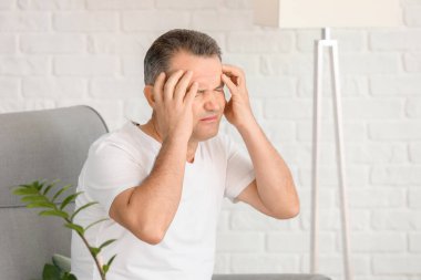 Evde baş ağrısı çeken olgun bir adam.