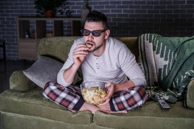 Akşam geç saatlerde evde film izleyen bir adam.