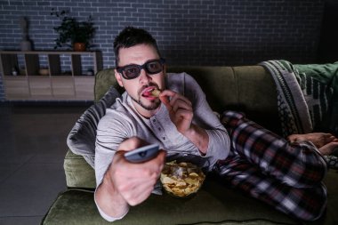 Akşam geç saatlerde evde film izleyen bir adam.