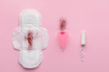 Regl pedi, bardak ve arka planda kırmızı parıltılı tampon. Regl konsepti