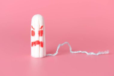 Renk arkaplanında kızgın yüzü çizilmiş bir tampon. Regl konsepti