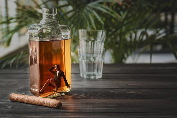 Giovane donna d'affari depressa seduta dentro una bottiglia di whisky sul tavolo di legno — Foto Stock
