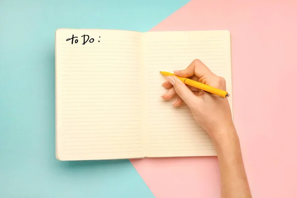 Mujer haciendo lista de tareas pendientes en el fondo de color —  Fotos de Stock