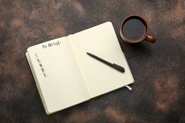 Cuaderno con una lista de tareas pendientes en blanco y una taza de té sobre fondo oscuro —  Fotos de Stock
