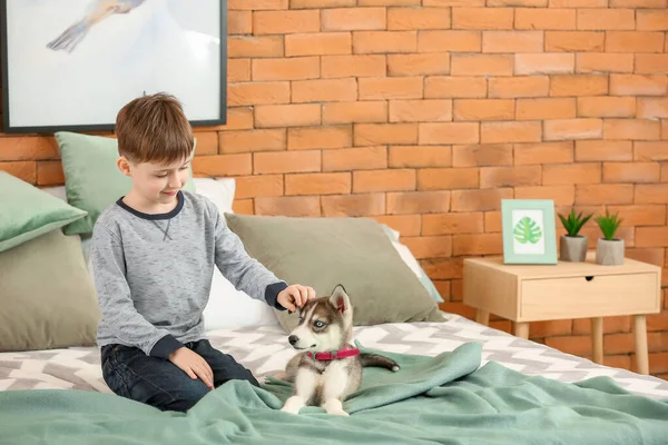 Маленький мальчик с милым щенком в спальне — стоковое фото