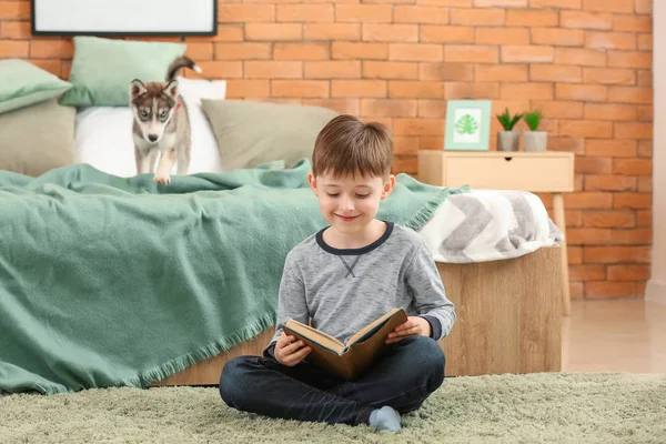 Petit garçon avec mignon chiot husky livre de lecture dans la chambre — Photo