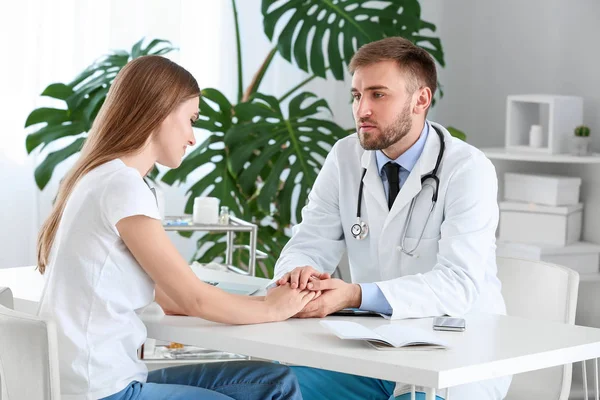 Male doctor calming sad female patient in clinic — Stock Photo, Image
