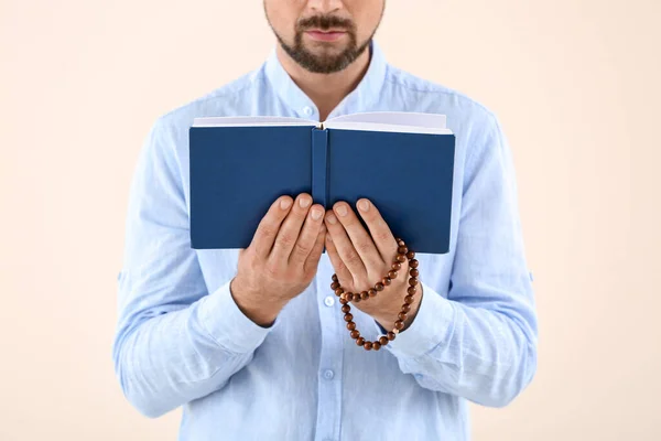 Muslimischer Mann mit Koran und Perlen auf hellem Hintergrund, Nahaufnahme — Stockfoto