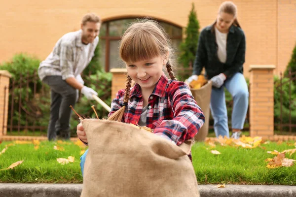 Family cleaning up autumn leaves outdoors — Stock Photo, Image