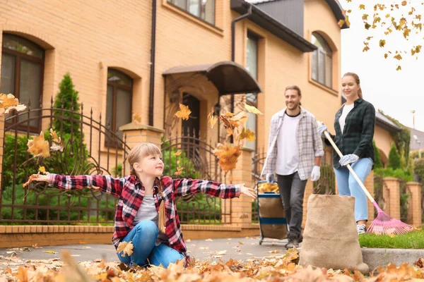 Family cleaning up autumn leaves outdoors — Stock Photo, Image