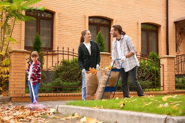 Family cleaning up autumn leaves outdoors — Stock Photo, Image