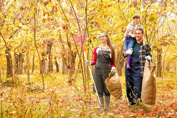 Family cleaning up autumn leaves outdoors — Stock Photo, Image