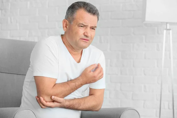 Mature man suffering from pain in elbow at home — Stock Photo, Image