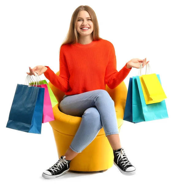 Schöne Frau mit Einkaufstaschen sitzt im Sessel auf weißem Hintergrund — Stockfoto