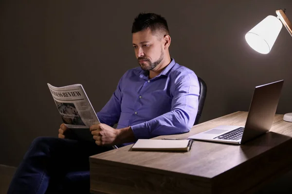 Homem lendo jornal no escritório tarde da noite — Fotografia de Stock