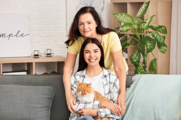 Mujer madura y su hija adulta con lindo gato en casa — Foto de Stock