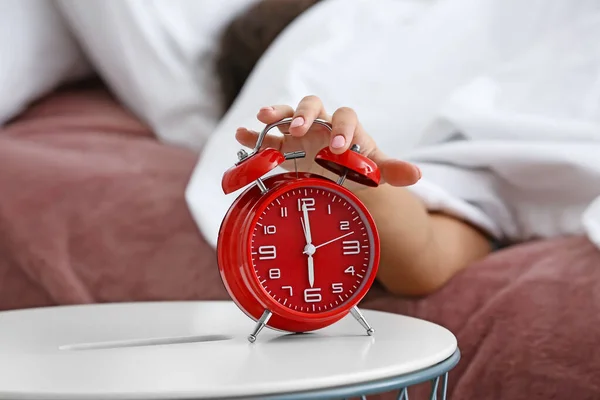 Woman switching off alarm clock in morning — Stock Photo, Image