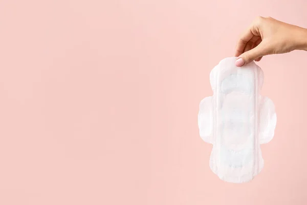 Female hand with menstrual pad on color background — Stock Photo, Image