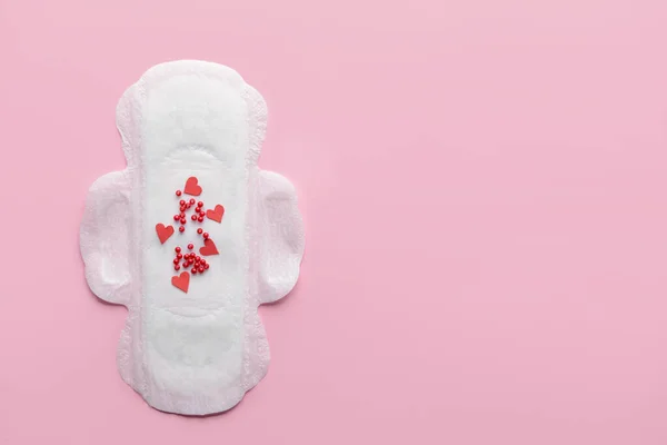 Pad Menstruasi dengan manik-manik merah pada latar belakang warna. Konsep menstruasi — Stok Foto