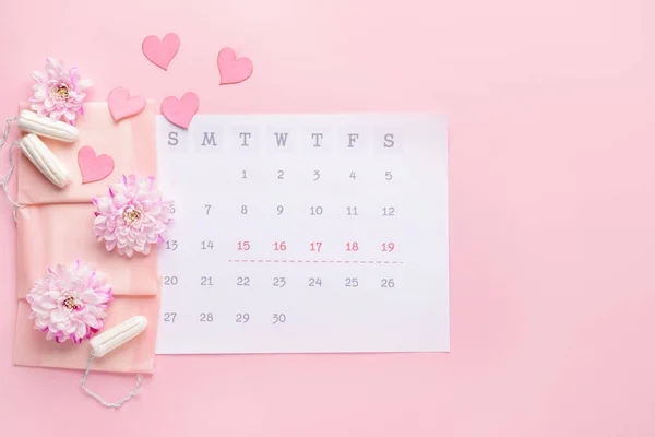 Menstruationskalender mit femininen Produkten auf farbigem Hintergrund — Stockfoto