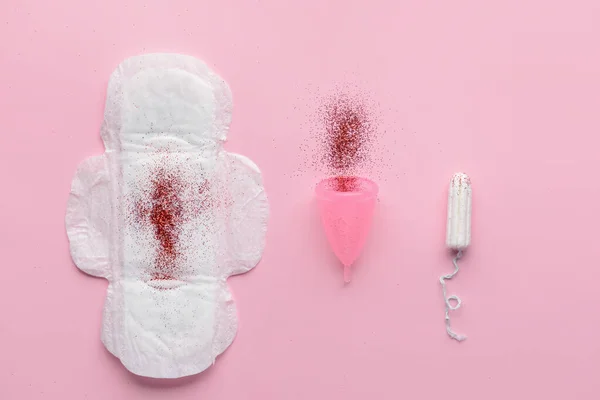 Menstruationskissen, Tasse und Tampon mit rotem Glitzern auf farbigem Hintergrund. Menstruationskonzept — Stockfoto