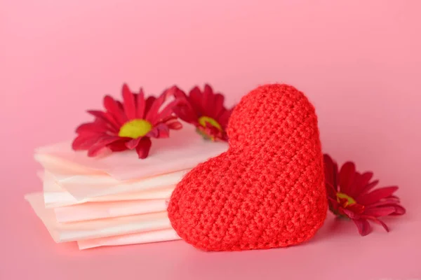 Klocki menstruacyjne z czerwonym sercem i kwiaty na tle koloru. Koncepcja menstruacji — Zdjęcie stockowe