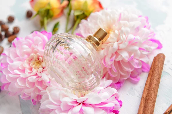 Bottle of perfume with cinnamon and flowers on white background — Stock Photo, Image