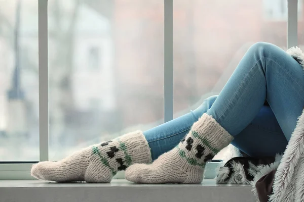在家里，穿着针织袜子坐在窗台上的年轻女子 — 图库照片