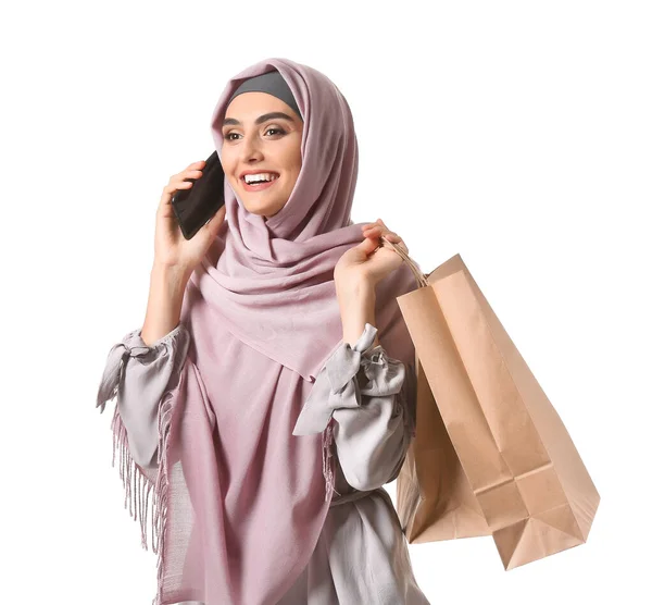 Mooie Arabische vrouw met boodschappentassen praten per mobiele telefoon op witte achtergrond — Stockfoto