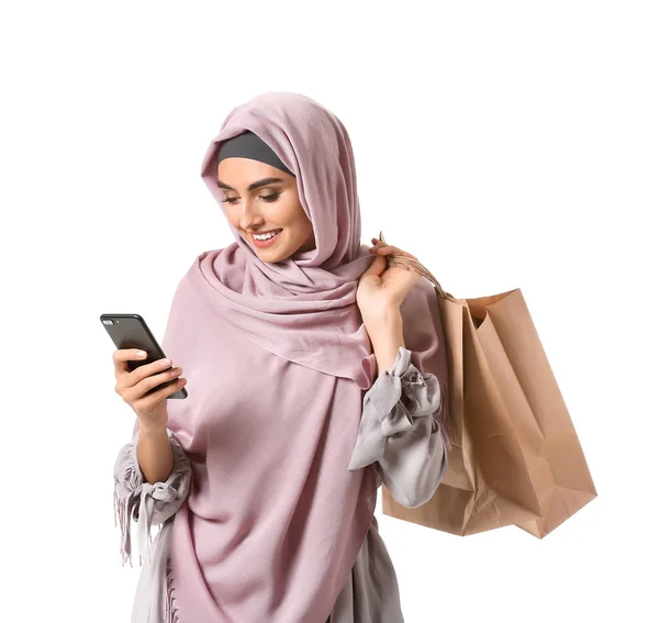 Gyönyörű arab nő bevásárló táskák és mobiltelefon fehér háttér — Stock Fotó