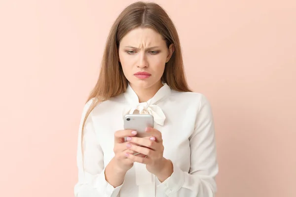 Sad businesswoman with mobile phone on color background — Stock Photo, Image