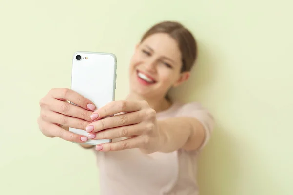 Happy woman taking selfie with mobile phone on color background, closeup — Stock Photo, Image