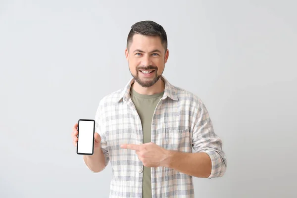 Älterer Mann mit Handy auf hellem Hintergrund — Stockfoto