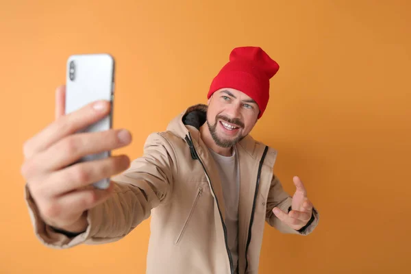 Hombre maduro con teléfono móvil tomando selfie sobre fondo de color — Foto de Stock