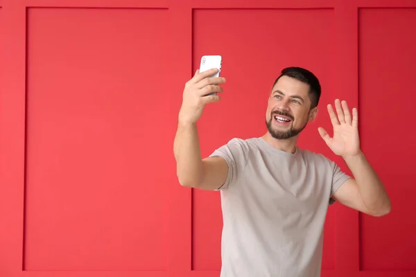 Hombre maduro con teléfono móvil tomando selfie sobre fondo de color — Foto de Stock