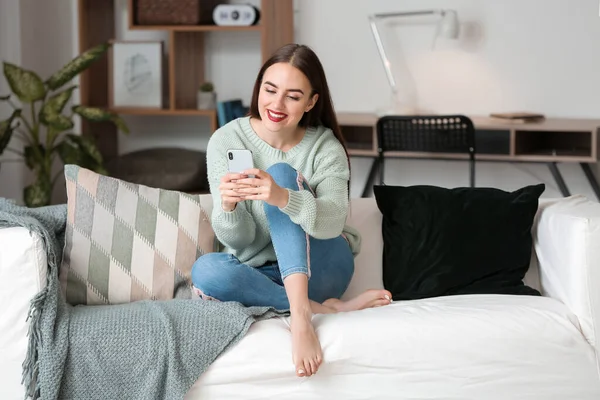 Beautiful young woman with mobile phone at home — Stock Photo, Image