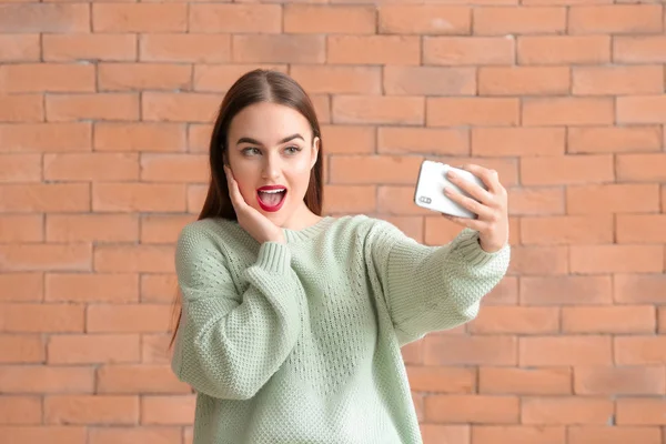 Krásná mladá žena přičemž selfie na cihlovém pozadí — Stock fotografie