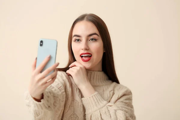 Beautiful young woman taking selfie on light background — Stock Photo, Image