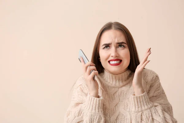 Nervous young woman with mobile phone on light background — Stock Photo, Image